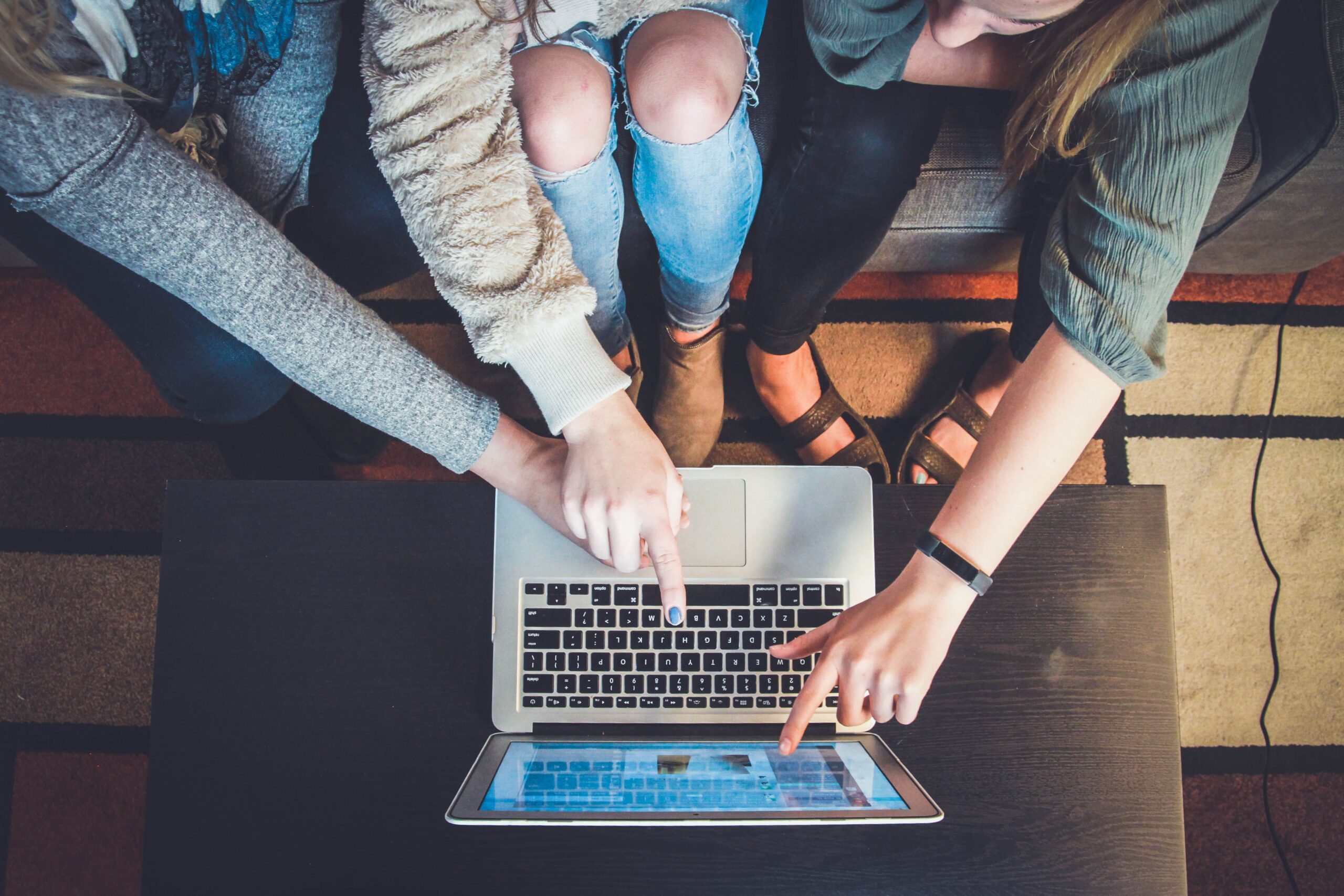 3 Menschen zeigen auf Laptop